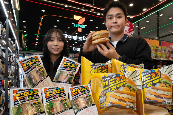 모델들이 세븐일레븐에서 새롭게 선보이는 '한도초과' 시리즈 샌드위치와 햄버거를 소개하고 있다. [사진=세븐일레븐]