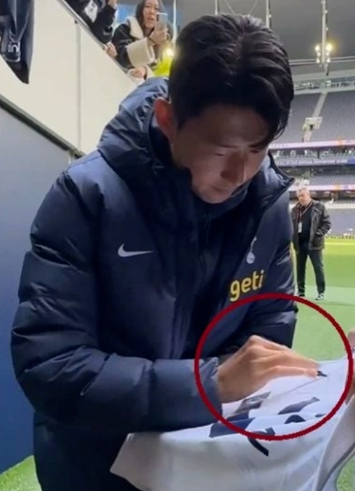 한국 대표팀 주장 손흥민(32&middot;토트넘)이 이강인(23&middot;파리 생제르맹)등과 물리적 충돌 과정에서 손가락이 탈구된 것으로 알려진 가운데, 팬에게 사인을 해주는 도중 후유증으로 인한 고통을 느끼는 모습이 포착됐다. [사진=온라인 커뮤니티]