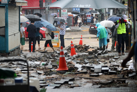 9일 오전 서울 관악구 신대방역 1번출구 인근 보도블럭이 폭우로 인해 파손 돼 관계자들이 작업을 하고 있다. [사진=뉴시스]
