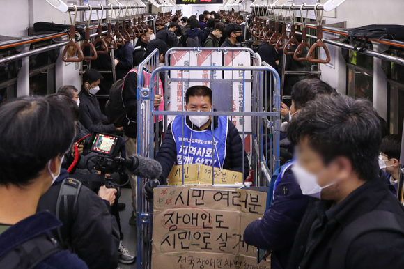 전국장애인차별철폐연대(전장연) 회원들이 25일 오전 서울 용산구 삼각지역에서 장애인권리예산 등을 촉구하는 '제41차 출근길 지하철 탑니다' 시위를 하고 있다. [사진=뉴시스]