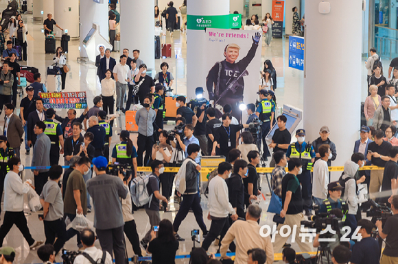미국 조지아주 포크스턴 이민세관단속국(ICE) 구금 시설에서 체포·구금됐다 풀려난 한국인 316명이 탑승한 전세기가 12일 인천국제공항 2터미널에 도착한 가운데, 이제석 이제석광고연구소 대표가 공항 입국장에서 트럼프 미국 대통령 얼굴이 담긴 플래카드 퍼포먼스를 펼치고 있다. [사진=정소희 기자]