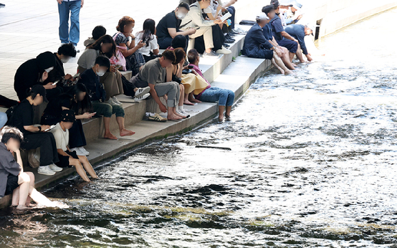 지난달 23일 서울 중구 청계천 모전교 아래에서 시민과 외국인 관광객 등이 더위를 식히고 있다. [사진=뉴시스]