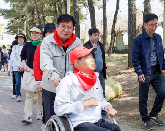 박강수 마포구청장이 장애인의 안전한 이동을 위해 휠체어 운전을 돕고 있다. [사진=마포구]