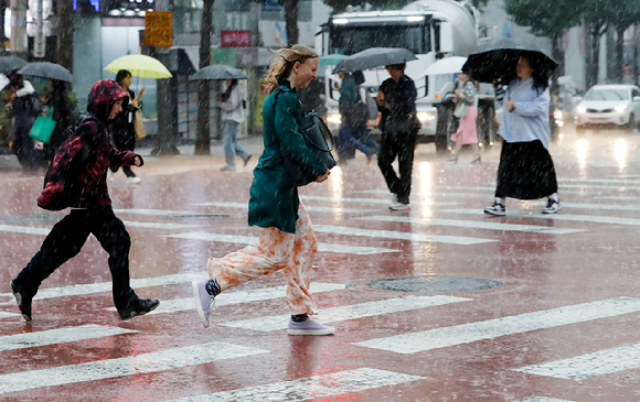 서울 충무로에서 우산을 챙기지 못 한 외국인이 황급히 뛰어가고 있다. [사진=뉴시스]