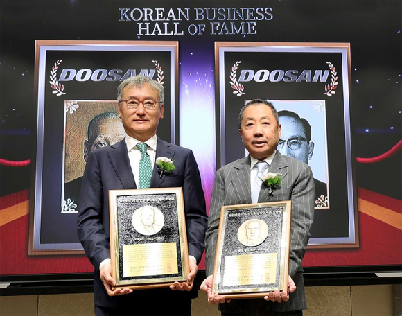 24일 서울 이화여대 경영대학 60주년 기념홀에서 열린&lsquo;대한민국 기업가 명예의 전당&rsquo;헌액식에서 박정원 두산그룹 회장(오른쪽)이 헌액 기념패를 들고 양희동 한국경영학회 회장(왼쪽)과 함께 기념촬영을 하고 있다. [사진=두산]