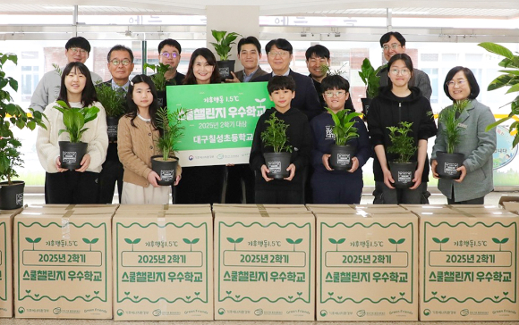 지난 9일 더현대 대구 임직원들이 기후에너지환경부 탄소중립 프로그램 '기후행동 1.5℃ 스쿨챌린지'에서 초등학교 부문 대상을 받은 대구 칠성초등학교를 방문해 공기정화식물을 전달하고 학생 및 교사들과 기념사진을 찍고 있다. [사진=현대백화점]