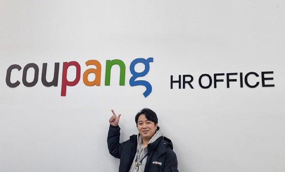 지난해 말 승진하며 CFS 최연소 인사팀장(조직장급)이 된 김성태(32) 씨가 쿠팡 로고 앞에서 포즈를 취하고 있다. [사진=쿠팡]
