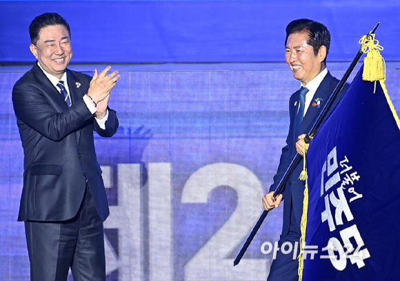 정청래 더불어민주당 신임 대표가 2일 경기 고양시 킨텍스에서 열린 제2차 임시전국당원대회에서 김병기 당대표 직무대행 겸 원내대표로부터 당기를 이양받고 있다. [사진=곽영래 기자]