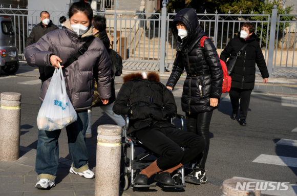 9일 중국 베이징의 마스크를 쓰고 휠체어에 앉은 한 노인이 가족의 부축을 받으며 병원을 방문하고 있다. [사진=뉴시스]