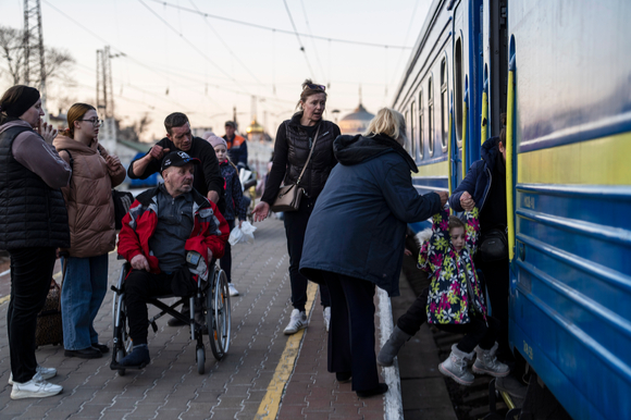 23일(현지시간) 우크라이나 남부 오데사의 기차역에서 사람들이 한 장애 노인의 피난 열차 탑승을 돕고 있다. [사진=오데사=AP/뉴시스]