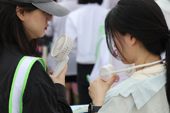 더운 날씨가 이어진 지난 22일 서울 용산구 노들섬에서 열린 체험형 뷰티&헬스(Beauty&Health) 축제 '2025 올리브영 페스타'에서 참관객들이 휴대용 선풍기로 더위를 식히고 있다. [사진=연합뉴스]