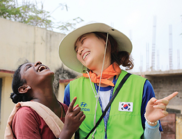 해피무브 봉사단에 참여한 자원봉사자가 현지 여성과 대화를 나누며 환하게 웃고 있다. [사진=현대차그룹]