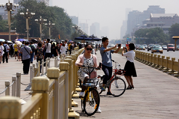베이징 천안문 광장 앞 자전거도로에서 자전거를 타던 시민들이 사진을 찍고 있다. [사진=AP/뉴시스]