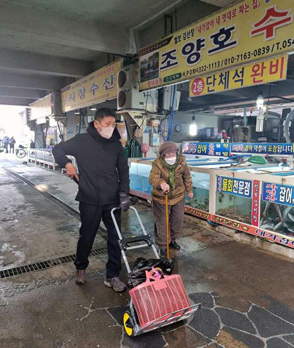 지난 18일 영덕군청 직원이 강구시장에서 어르신 장바구니 들어주기 봉사를 하고 있다. [사진=영덕군청]