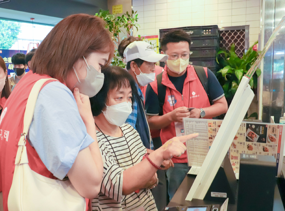 롯데정보통신 직원들이 금천장애인종합복지관에서 키오스크 교육 봉사를 진행하고 있다 [사진=롯데정보통신]