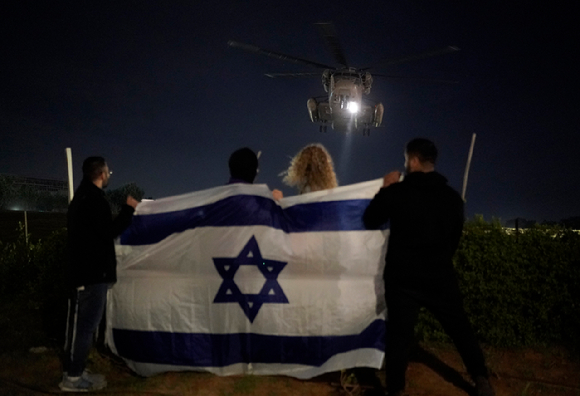 28일(현지시각) 이스라엘 텔아비브의 이칠로프 병원에서 이스라엘 국기를 펼쳐 든 사람들이 하마스로부터 풀려난 인질들을 태운 헬기가 착륙하는 것을 지켜보고 있다. [사진=뉴시스]