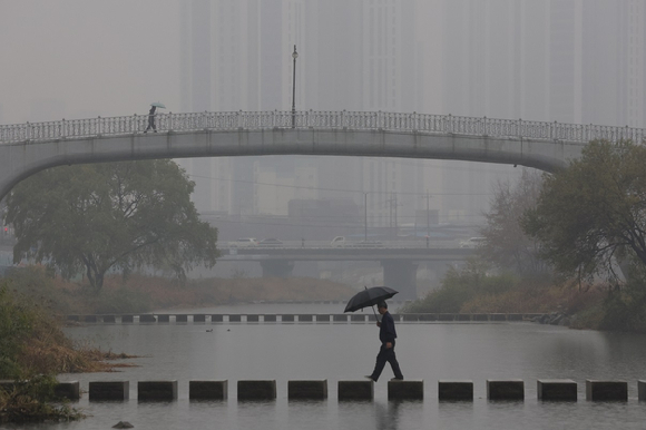 경기도 의정부시 중랑천에서 시민들이 우산을 쓰고 이동하고 있다. [사진=연합뉴스]