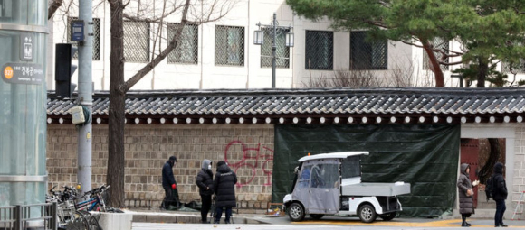 문화재청 궁능유적본부 직원들이 16일 오전 서울 종로구 국립고궁박물관 방향 경복궁 서편에서 스프레이 낙서로 훼손된 담벼락을 천으로 덮고 있다. [사진=뉴시스]