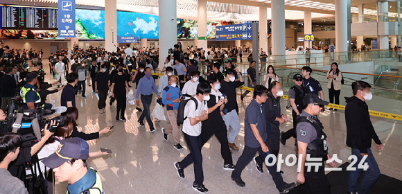 미국 이민당국에 의해 조지아주에 구금됐던 한국인 근로자들이 12일 인천국제공항 제2여객터미널 입국장을 나서고 있다. 작업복을 입은 상태로 귀국하는 근로자의 모습. [사진=정소희 기자]