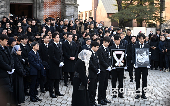 9일 서울 중구 명동성당에서 열린 故 안성기의 장례 미사가 끝난 뒤 영결식을 위해 고인의 영정과 금관문화훈장을 든 배우 정우성, 이정재가 영결식장으로 향하고 있다. [사진=곽영래 기자]
