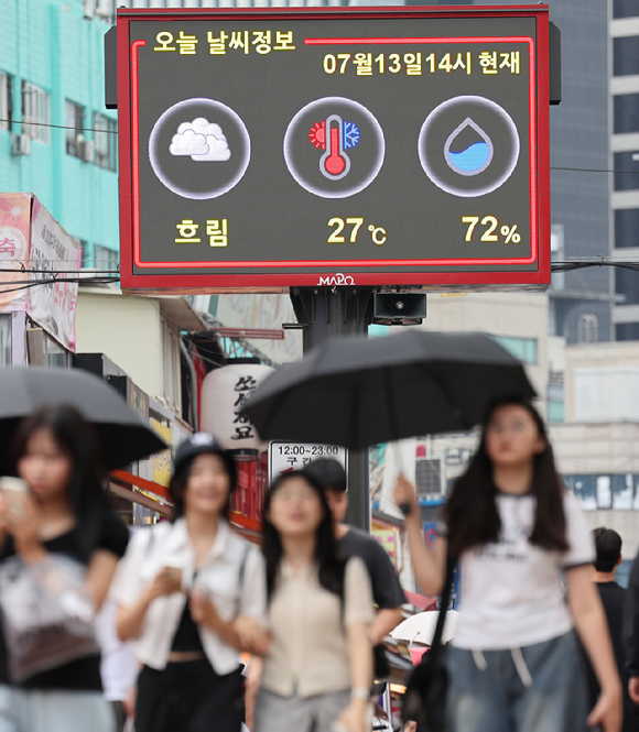 폭염 와중에 비 예보로 시민들이 우산을 쓰고 이동하고 있다. [사진=연합뉴스]