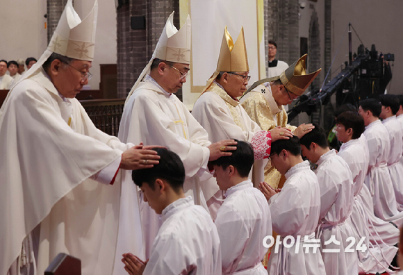 1일 서울 중구 명동대성당에서 열린 2024년 천주교 서울대교구 부제 서품식에서 부제 수품자들이 정순택 대주교를 비롯한 교구 주교·사제단에게 안수받고 있다. [사진=사진공동취재단]