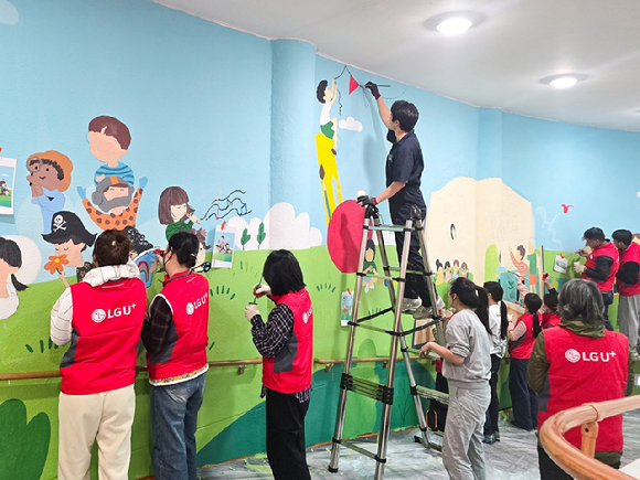 사진은 LG유플러스 임직원들이 충주성모학교 담장에 벽화를 그리고 있는 모습 [사진=LGU+]