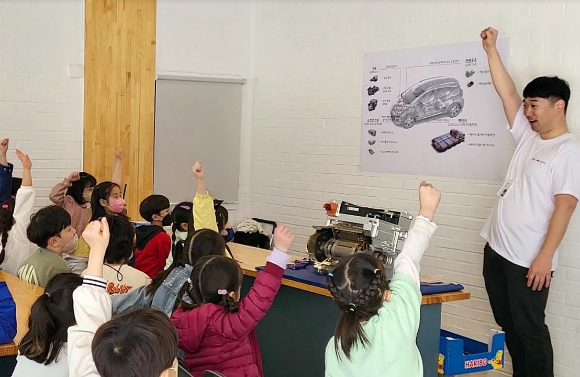 LG마그나 직원이 LG마그나가 생산한 부품을 교구로 활용해 학생들에게 전기차에 대해 설명하고 있다. [사진=LG마그나 ]
