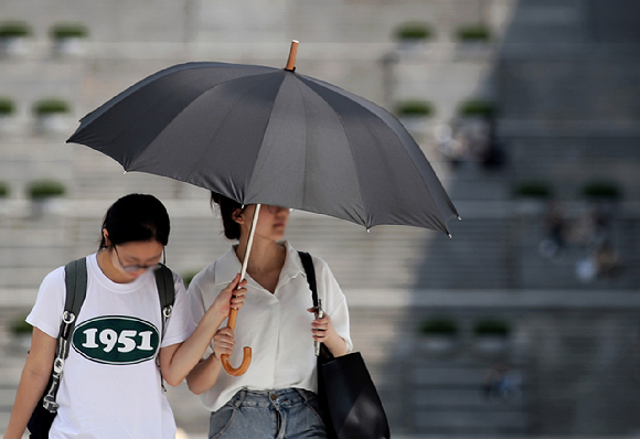 지난해 서울 서대문구 이화여자대학교에서 학생들이 양산을 쓰고 걸어가고 있다. [사진=뉴시스]