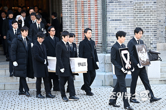 9일 서울 중구 명동성당에서 열린 故 안성기의 장례 미사가 끝난 뒤 영결식을 위해 고인의 영정과 금관문화훈장을 든 배우 정우성, 이정재가 영결식장으로 향하고 있다. [사진=곽영래 기자]