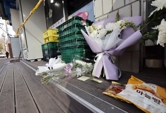 직원이 살해된 경기 시흥시의 한 편의점 앞에 추모의 글귀가 적힌 쪽지와 국화 꽃다발, 간식 등이 놓여있다. [사진=연합뉴스]