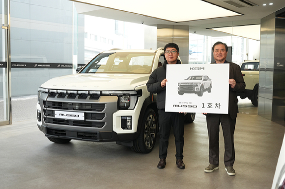 지난 19일 KGM 익스피리언스 센터 일산에서 열린 &lsquo;무쏘 1호차 전달식&rsquo;에서 1호차 주인공 이미남 대표(왼쪽)와 권교원 사업부문장이 기념 촬영을 하고 있다. [사진=KGM]