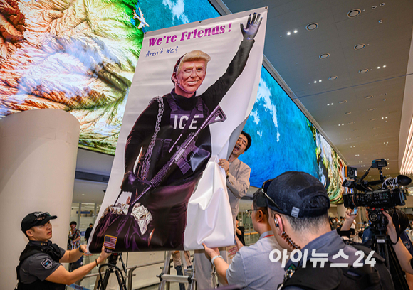 미국 조지아주 포크스턴 이민세관단속국(ICE) 구금 시설에서 체포·구금됐다 풀려난 한국인 316명이 탑승한 전세기가 12일 인천국제공항 2터미널에 도착한 가운데, 이제석 이제석광고연구소 대표가 공항 입국장에서 트럼프 미국 대통령 얼굴이 담긴 플래카드 퍼포먼스를 펼치고 있다. [사진=정소희 기자]