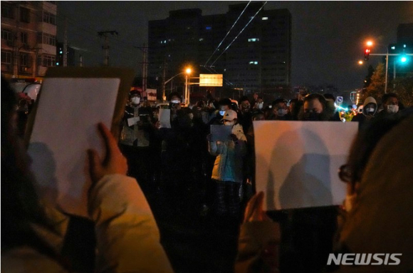 지난 27일 중국 베이징에서 코로나19 봉쇄 정책에 항의하는 시위대가 '백지'를 들고 구호를 외치고 있다. [사진=뉴시스]