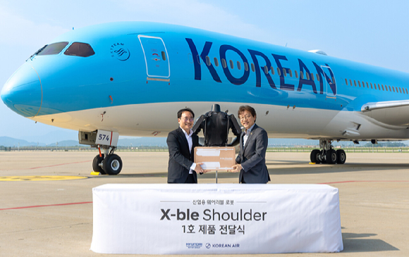 (왼쪽부터)현동진 현대차∙기아 로보틱스랩 상무와 정현보 대한항공 항공우주사업본부 상무가 지난 8일 인천시 중구 대한항공 항공기 정비고에서 엑스블 숄더 1호 전달식 후 기념사진을 촬영하고 있다. [사진=현대자동차그룹]