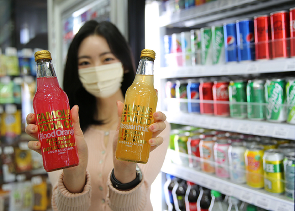 GS25에서 한 직원이 페이머스소다 블러드 오렌지와 패션후르츠맛 상품을 소개하고 있다. [사진=GS리테일]