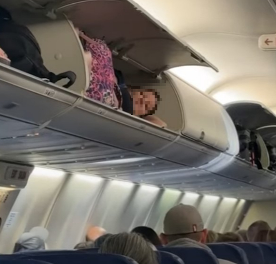 항공기의 좌석 위 기내수화물 짐칸에 한 여성이 누워 있는 장면이 화제다. [사진=틱톡 캡쳐]
