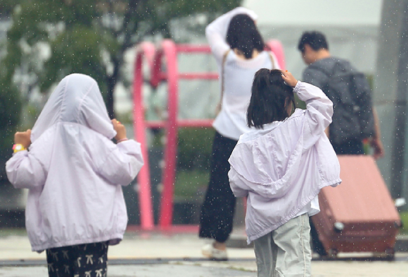 소나기가 내린 25일 오전 서울 종로구 광화문광장에서 아이들이 비를 피하기 위해 뛰고 있다. 2025.8.25 [사진=연합뉴스]