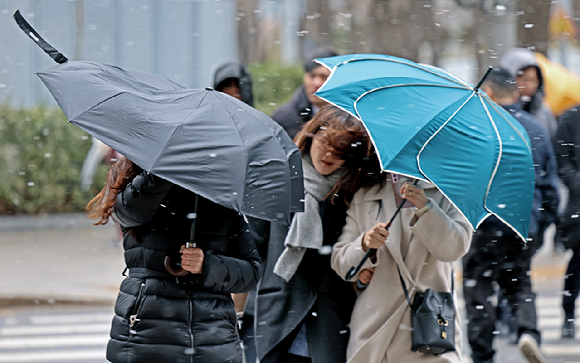 오후 한때 진눈깨비와 돌풍이 몰아친 지난 5일 서울 시내 한 거리에서 시민들이 우산을 쓰고 이동하고 있다. [사진=뉴시스]