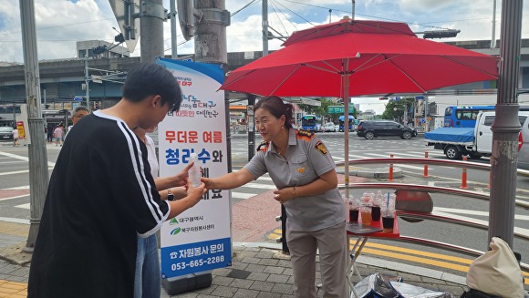 대구 북구자원봉사센터 봉사단원이 시민들에게 생수를 나눠주고 있다. [사진=북구청]