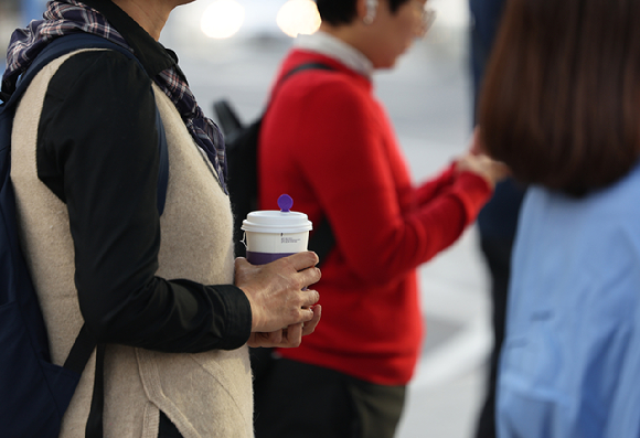 지난 8일 오전 서울 종로구 광화문광장 인근에서 한 시민이 음료를 들고 서 있다. [사진=연합뉴스]