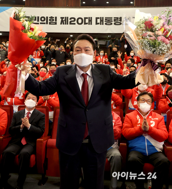 윤석열 대통령 당선인이 10일 새벽 서울 여의도 국회도서관에 마련된 '국민의힘 제 20대 대통령선거 개표상황실'을 찾아 꽃다발을 받은뒤, 취재진을 향해 포즈를 취하고 있다. [사진=김성진 기자]