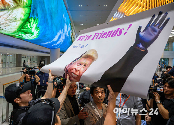 미국 조지아주 포크스턴 이민세관단속국(ICE) 구금 시설에서 체포·구금됐다 풀려난 한국인 316명이 탑승한 전세기가 12일 인천국제공항 2터미널에 도착한 가운데, 이제석 이제석광고연구소 대표가 공항 입국장에서 트럼프 미국 대통령 얼굴이 담긴 플래카드 퍼포먼스를 펼치고 있다. [사진=정소희 기자]