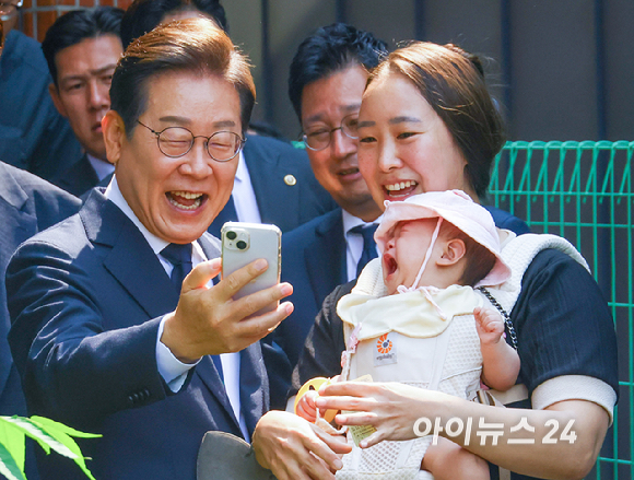 이재명 더불어민주당 대통령 후보가 제21대 대통령선거 사전투표 첫날인 29일 오전 서울 서대문구 구 신촌동주민센터에서 아기를 안은 어머니와 셀카를 찍고 있다. [사진=곽영래 기자]
