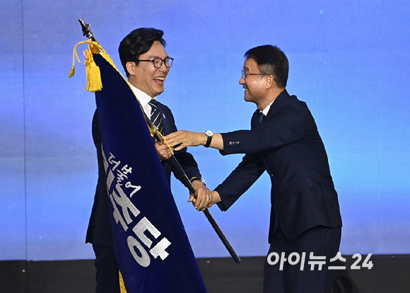 김민석 더불어민주당 신임 당 대표가 17일 대전 컨벤션센터에서 열린 제3회 더불어민주당 정기 전국당원대회에서 당 대표로 선출된 뒤 한병도 원내대표에게 당기를 건네받고 있다. [사진=곽영래 기자]
