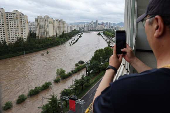 폭염 속 서울역 쪽방촌 인근 한 공원에서 주민이 쿨링포그를 맞으며 부채질을 하고 있다. [사진=연합뉴스]