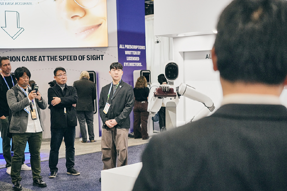 CES 2026 위로보틱스 부스에서 휴머노이드 로봇 알렉스(ALLEX)가 웨어러블 보행보조 로봇 &lsquo;윔 S(WIM S)&rsquo;를 손에 직접 들고 시연하고 있다. [사진=위로보틱스]