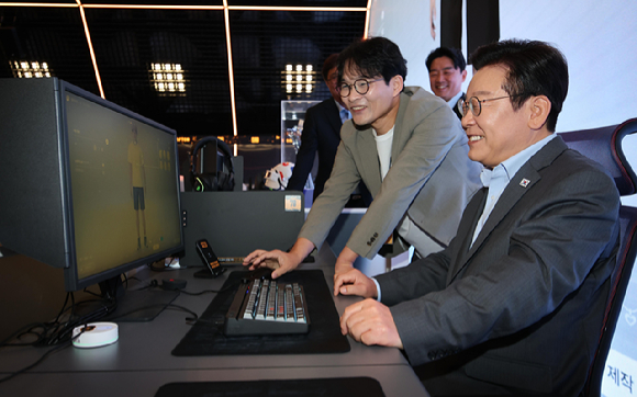 이재명 대통령이 지난 15일 서울 성동구에 위치한 크래프톤의 복합 문화공간 '펍지 성수'에서 AI기반 인생 시뮬레이션 게임 '인조이'를 체험하고 있다. 왼쪽은 김형준 인조이스튜디오 대표. [사진=연합뉴스]