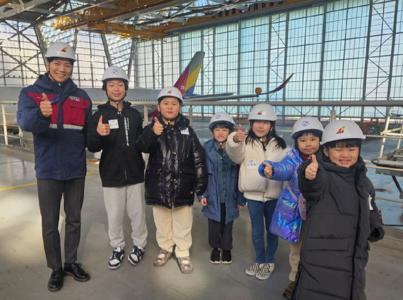 22일 인천 영종도 인천국제공항 아시아나항공 정비 격납고에서 &lsquo;Why? 항공과학 탐험교실&rsquo; 행사에 참가한 아시아나항공&middot;대한항공 직원 자녀들과 현직 정비사가 기념 촬영을 하고 있다. [사진=아시아나항공]
