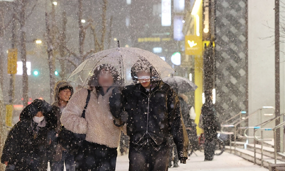 지난 4잋 서울 마포구 홍대 부근에 눈이 내리는 가운데 시민들이 우산을 쓰고 이동하고 있다. [사진=연합뉴스]